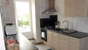 A modern kitchen with a black countertop, stainless steel range hood, and light wood cabinets. - Holiday Home "La Maison des Ormeaux" with Private Terrace and Wi-Fi (Ars-en-Ré)