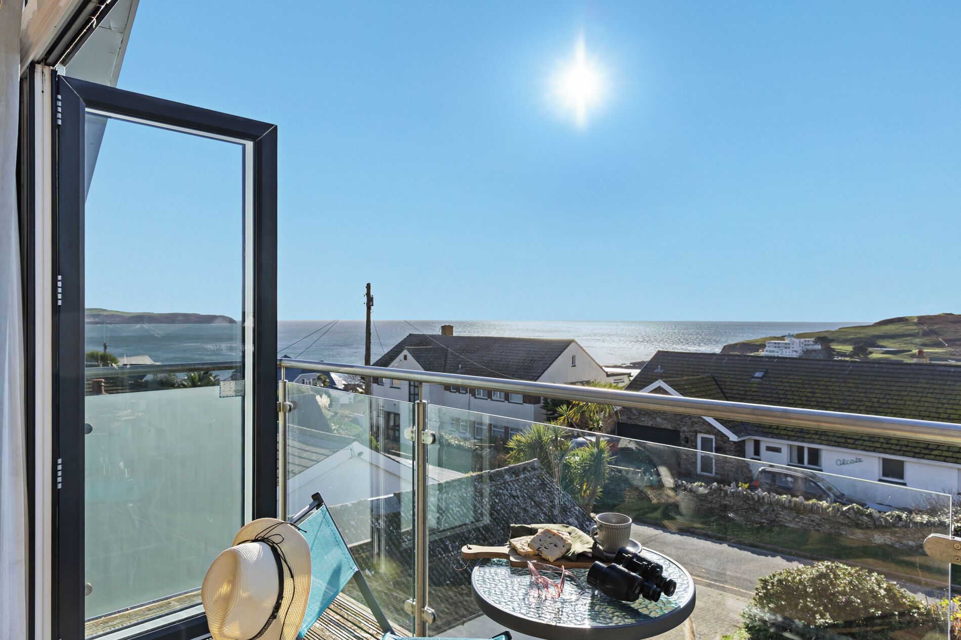 Ein Balkon mit Glasdoor, einem Hut, einer Kamera und einem Teller mit Essen.