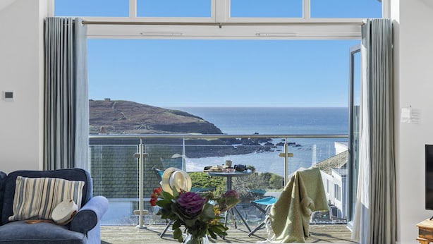 A room with a large sliding glass door leading to a balcony with a view of the sea and a hill. - Spring Tide, 3 bedrooms, Sea views, Bigbury on Sea (Bigbury on Sea, Kingsbridge)