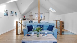 A spacious living room with a high ceiling, a kitchen in the background, and a dining area with a glass partition. - Spring Tide, 3 bedrooms, Sea views, Bigbury on Sea (Bigbury on Sea, Kingsbridge)