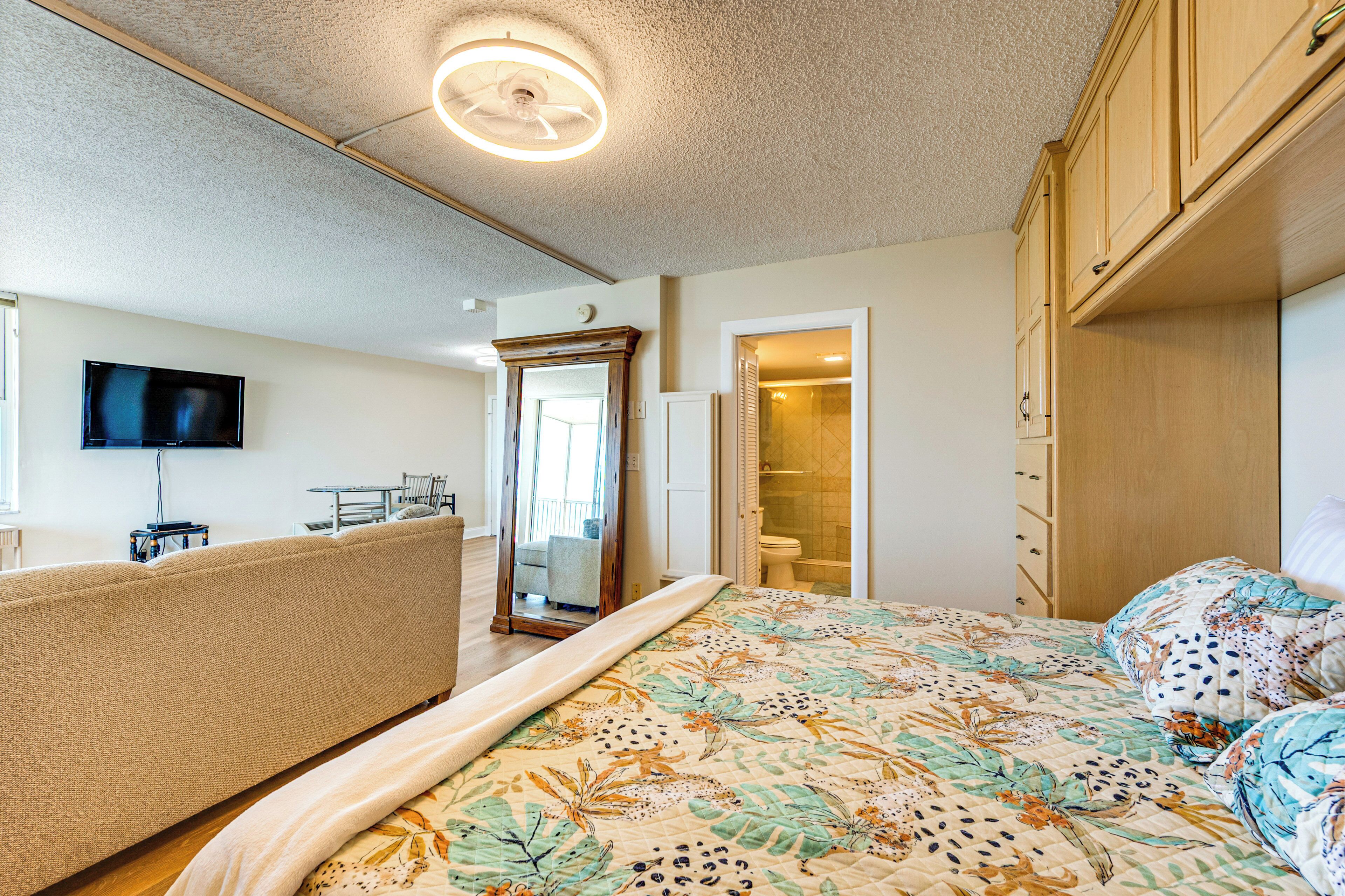 A bedroom with a bed, a television, a mirror, and a wardrobe.