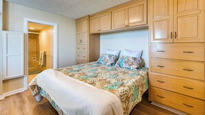 Une chambre à coucher avec un grand lit, des armoires en bois et un dressing.