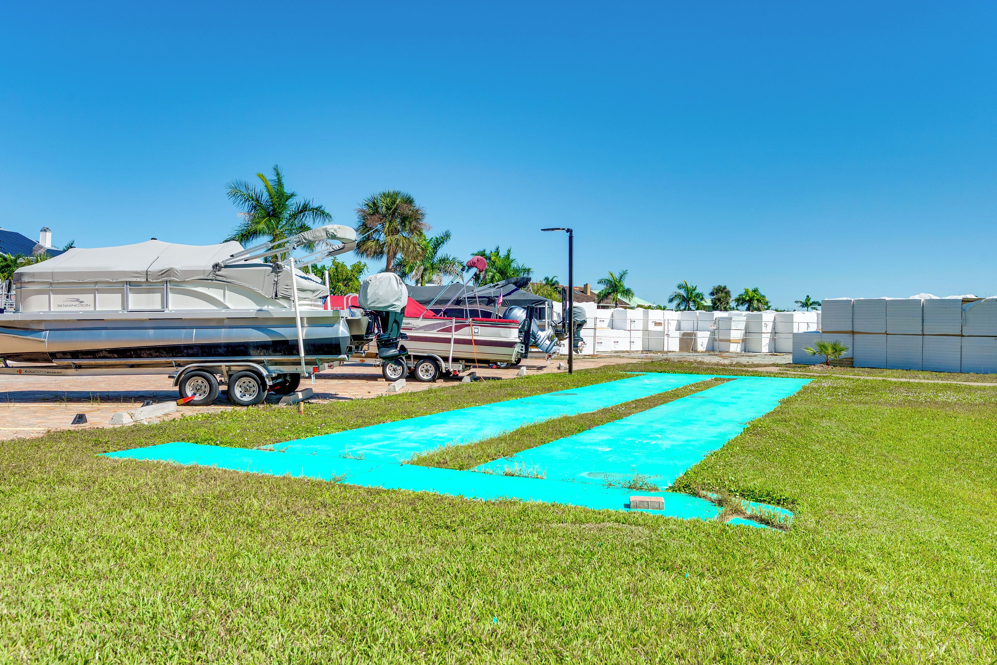 Une zone herbeuse avec un tapis bleu, une remorque et un bateau doté d’un auvent.