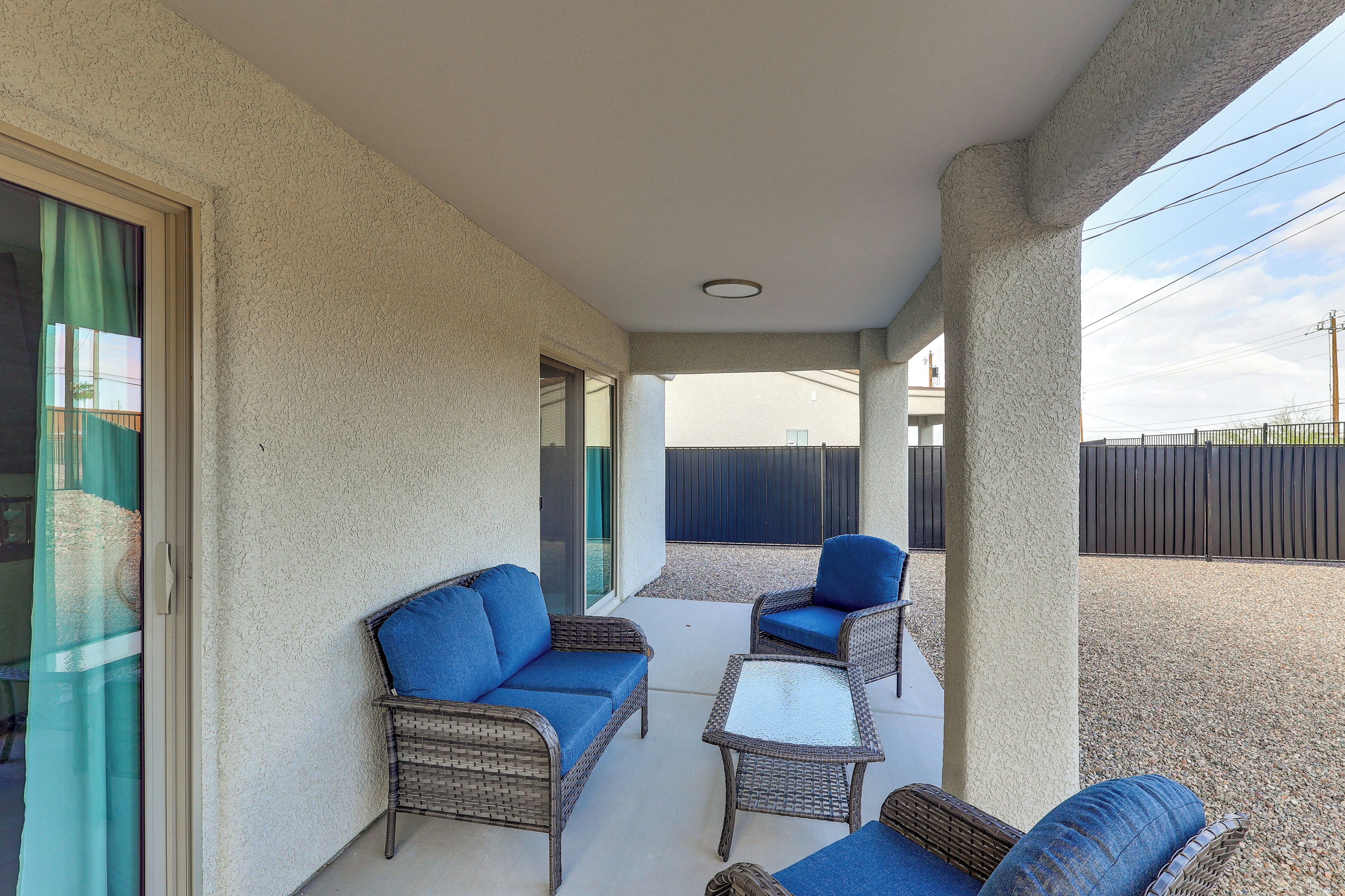 A covered patio area with wicker furniture and a glass door leading to a balcony.