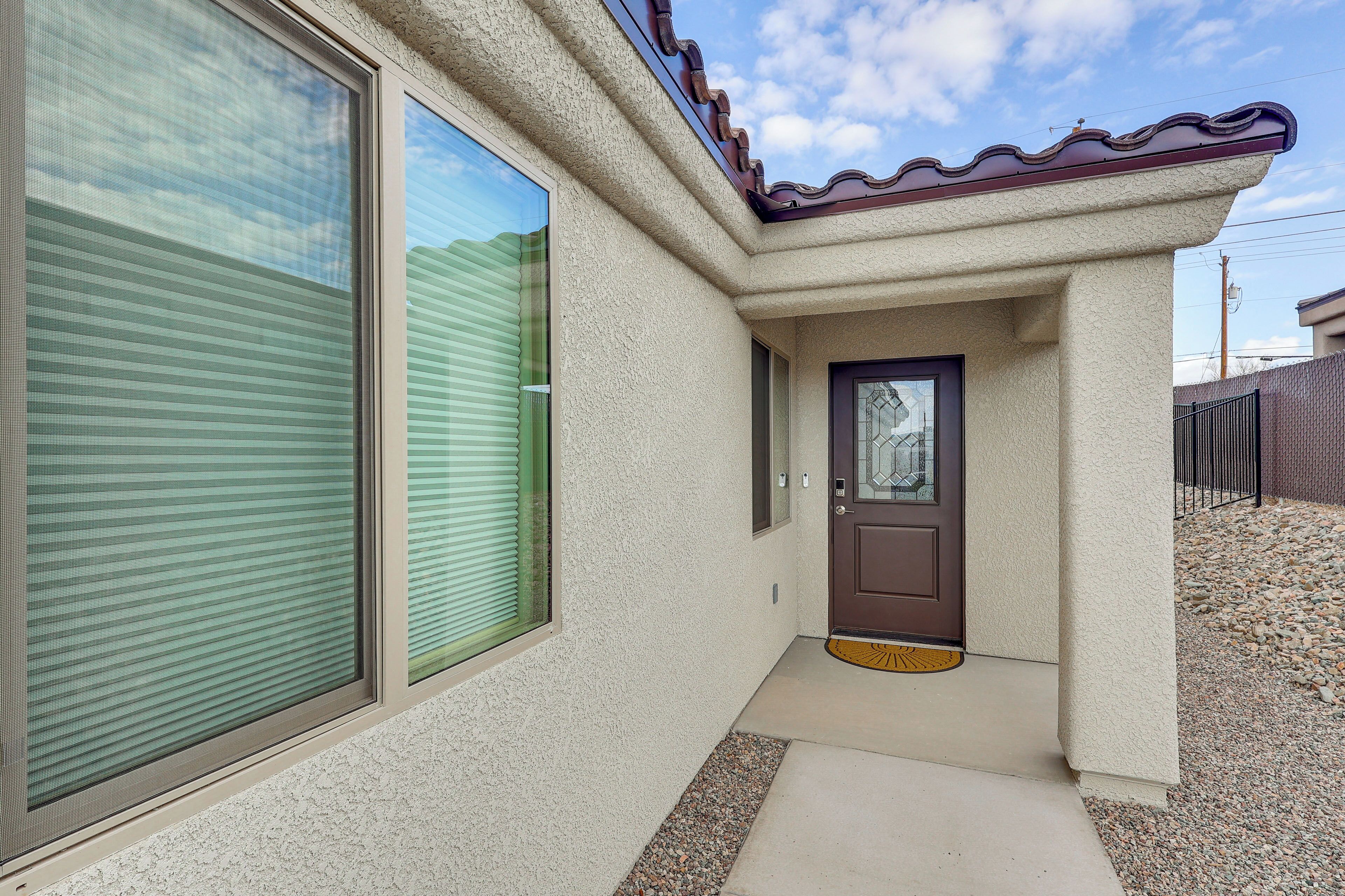 A house with a brown door, a window with blinds, and a textured exterior wall.