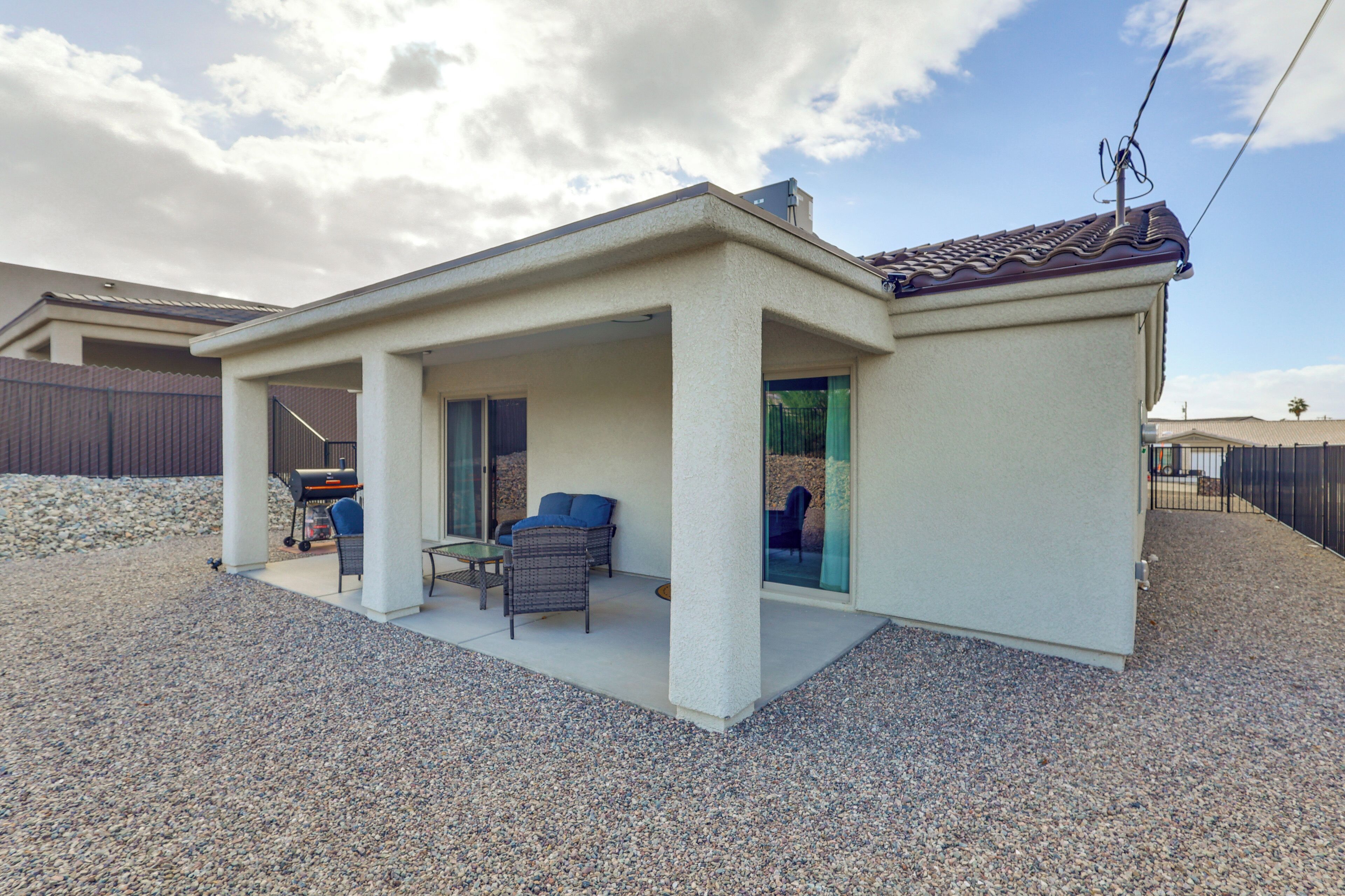A covered patio area with a grill, seating, and a view of the backyard.