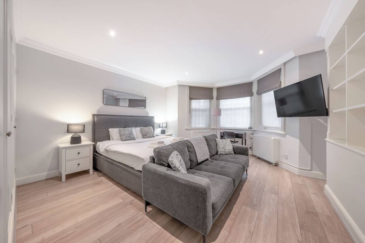 A modern bedroom with a bed, bedside table, lamp, and a TV mounted on the wall.