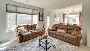A living room with two brown leather sofas, a glass coffee table with a vase of flowers, and large windows with blinds. - 13 Mi to Slopes: Cozy Home w/ Fenced Yard in Reno (Reno)