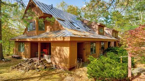 A two-story wooden cabin with a sloped metal roof, large windows, and a porch with outdoor seating. - 6 Mi to Okemo! Family Townhome in Lakeside Resort (Plymouth)