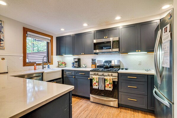 A modern kitchen with dark cabinets, stainless steel appliances, and a large island. - 6 Mi to Okemo! Family Townhome in Lakeside Resort (Plymouth)