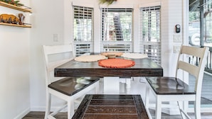 A dining area with a dark wooden table, white chairs, and a decorative pine cone on the wall. - Pet-friendly Show Low Cabin w/ Trail Access! (Show Low)