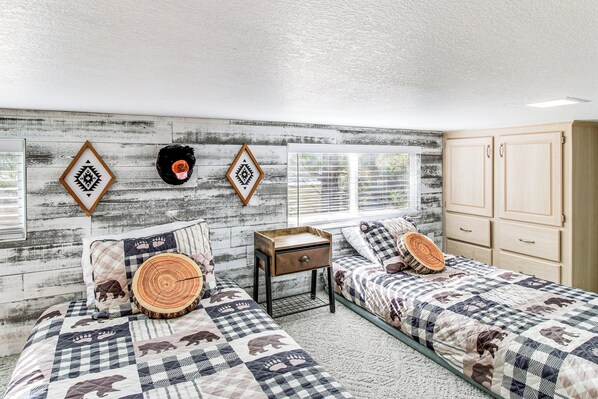A bedroom with two beds, a wooden headboard, a small wooden nightstand, and a wardrobe. - Pet-friendly Show Low Cabin w/ Trail Access! (Show Low)