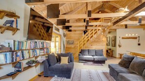 A spacious living area with a staircase, bookshelves, and modern furniture. - 7 Mi to Bilger's Rocks: Secluded 7-acre Retreat (Curwensville)