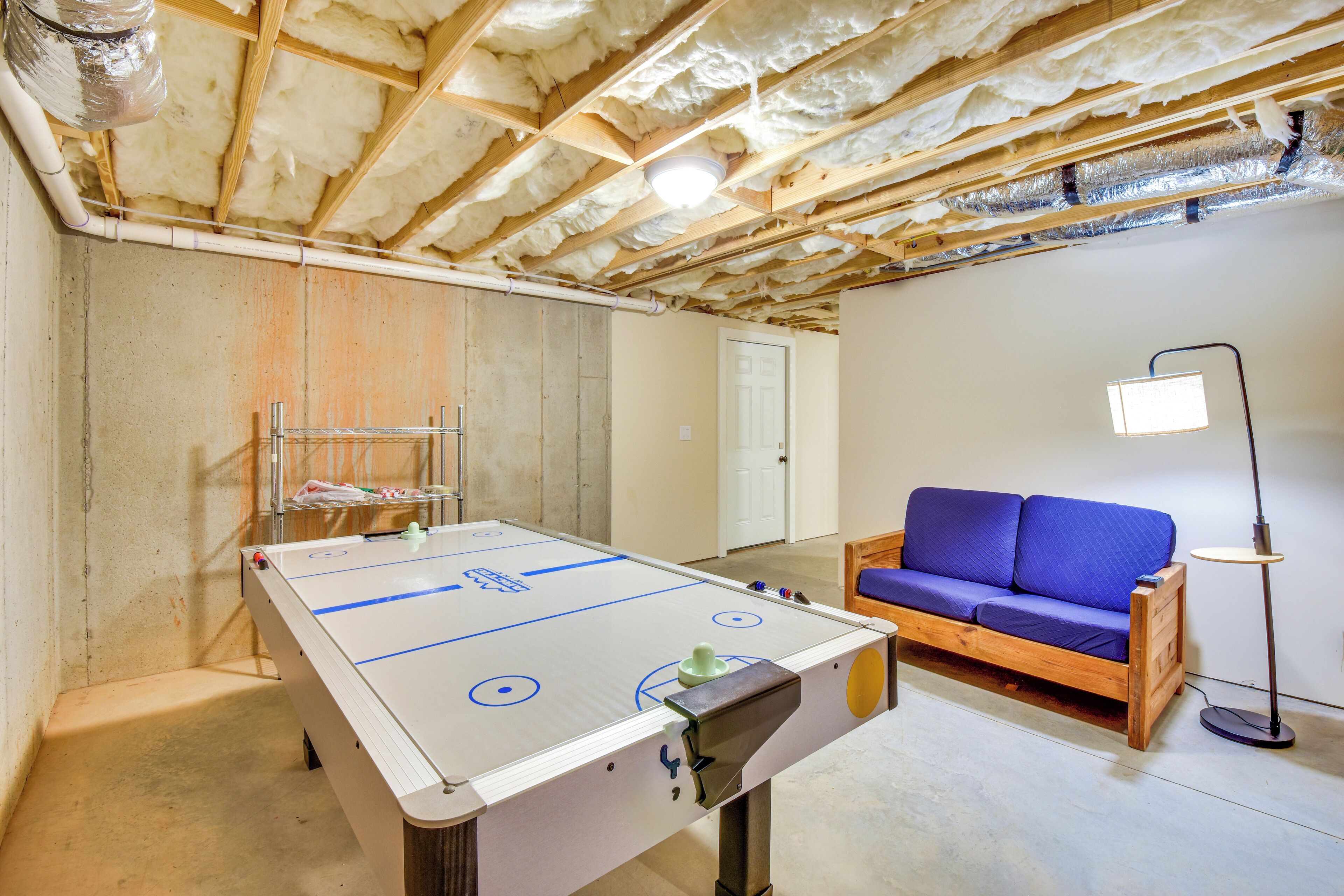 A room with a foosball table, a sofa, and a lamp.
