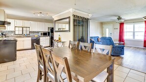 Une cuisine spacieuse avec un coin repas, une grande table en bois et un ventilateur de plafond.