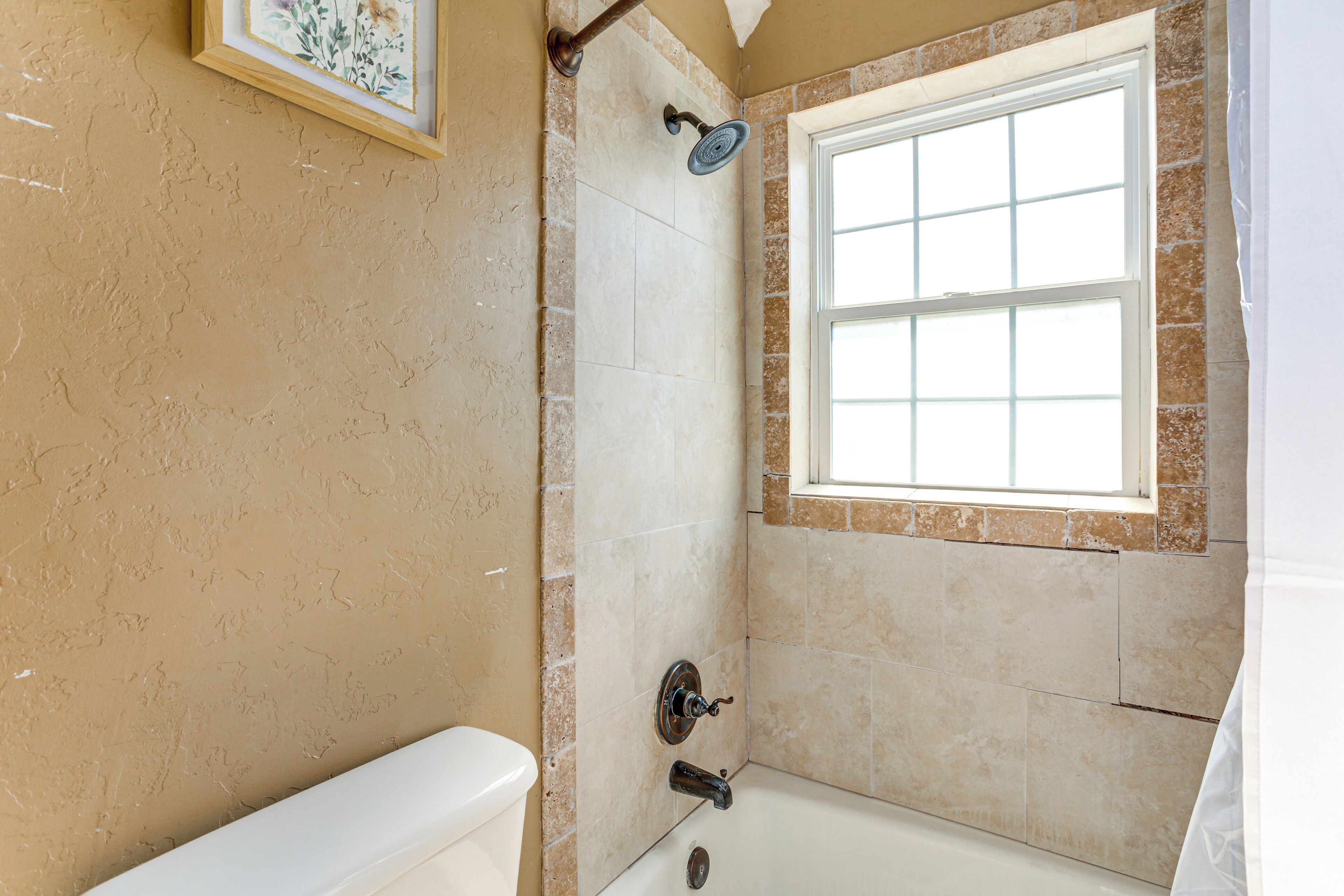 A bathroom with a bathtub, a window, and a shower.