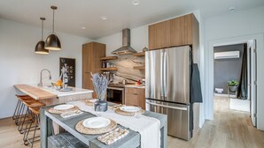 Une cuisine moderne dotée d’un îlot central, d’appareils électroménagers en acier inoxydable et de meubles de rangement en bois.