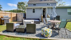 A backyard with a patio area featuring wicker furniture, a grill, and an umbrella. - Beach Days & Dtwn Charm! Cape Charles Cottage (Cape Charles)