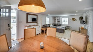 A modern living room with a wooden dining table, a sofa, and a large pendant light. - Beach Days & Dtwn Charm! Cape Charles Cottage (Cape Charles)