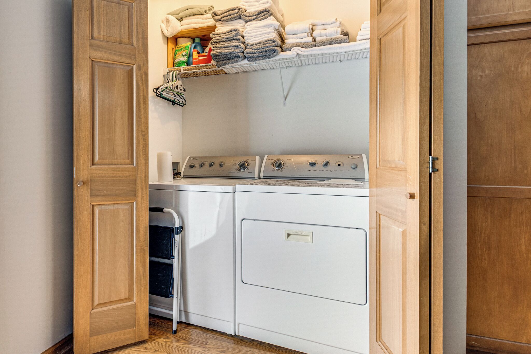 Une buanderie avec une étagère où sont pliées et empilées des serviettes, un lave-linge et un sèche-linge.