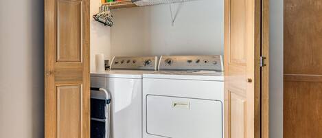 A laundry room with a stacked shelf of folded towels, a washing machine, and a dryer.