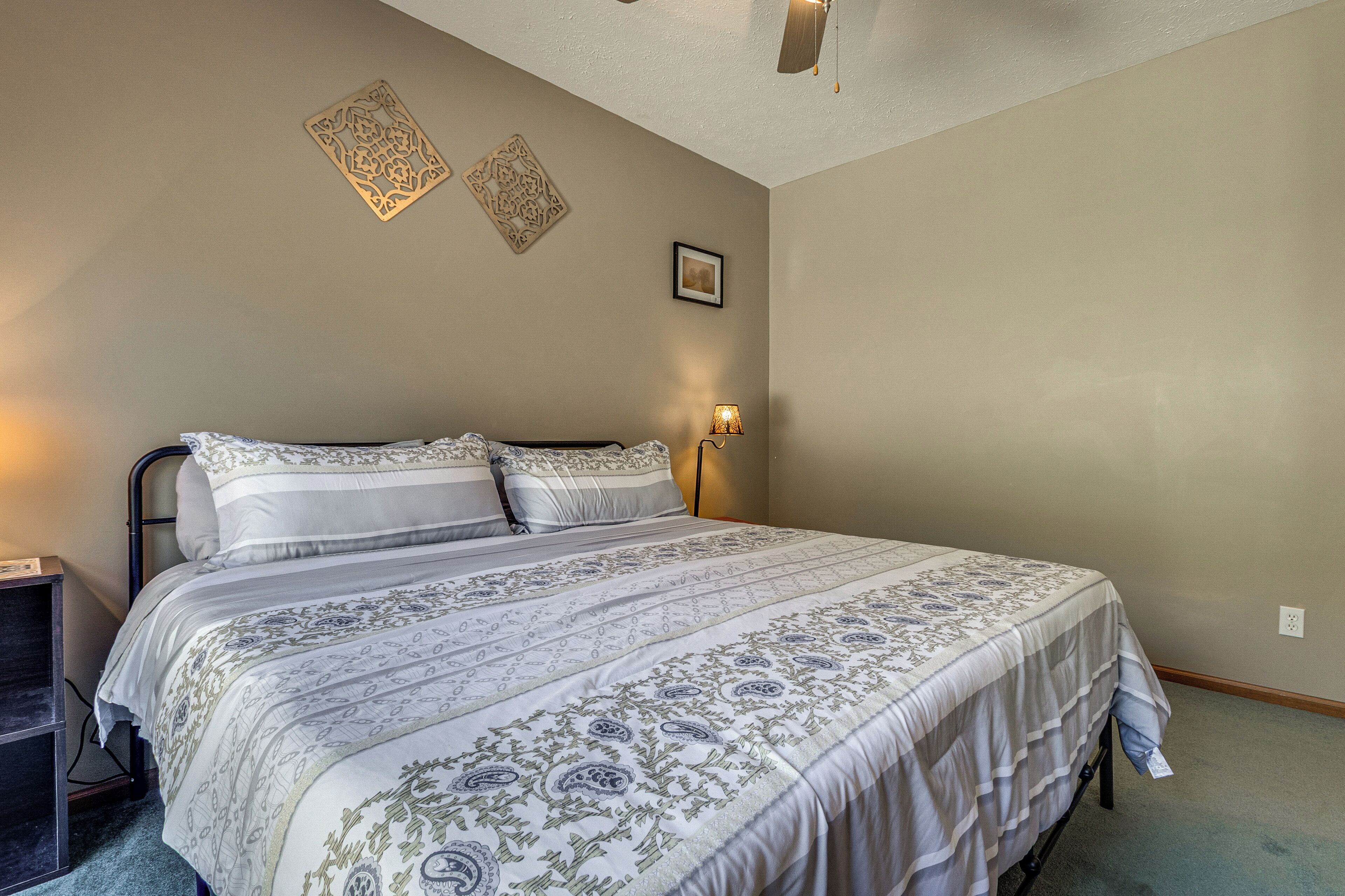 A bedroom with a large bed, a bedside table, and a wall-mounted lamp.