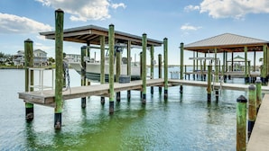 A pier with a covered seating area and a gazebo, extending into a calm body of water.