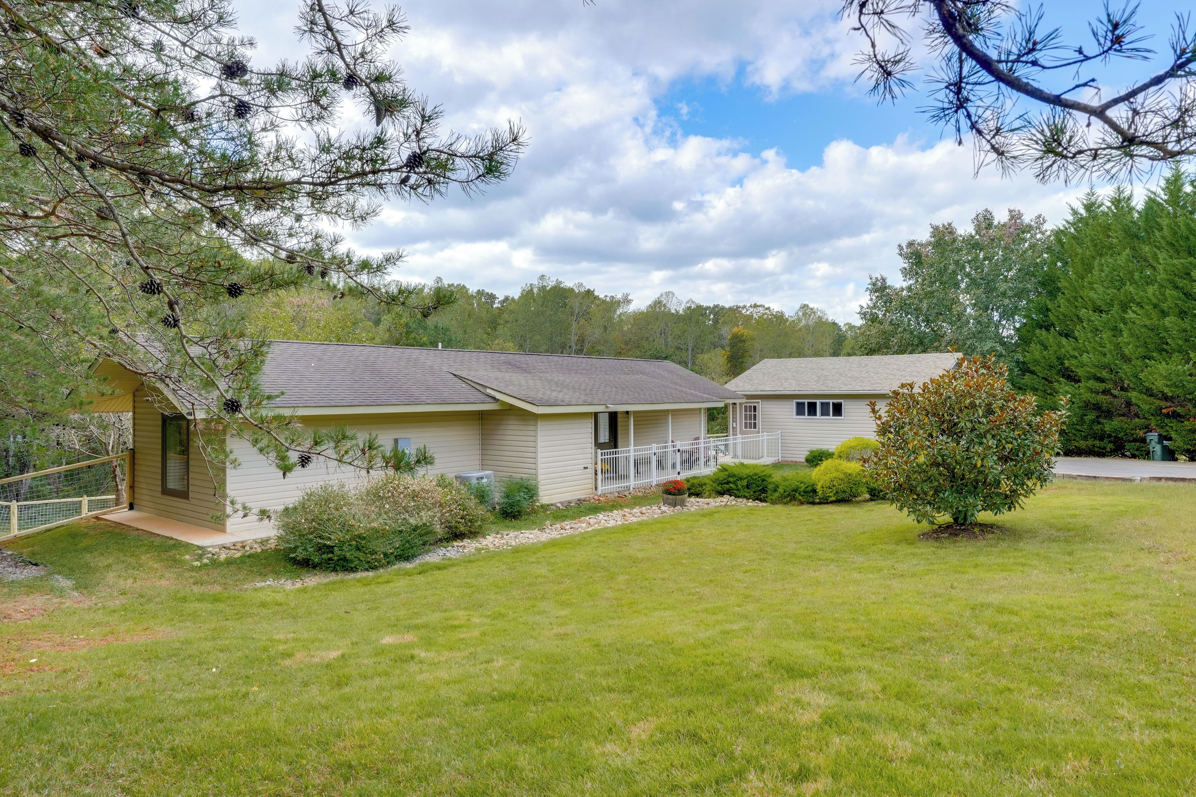 A two-story house with a front porch, a small garden, and a tree in the yard.