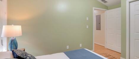 A bedroom with a bed, a lamp, and a door leading to another room.