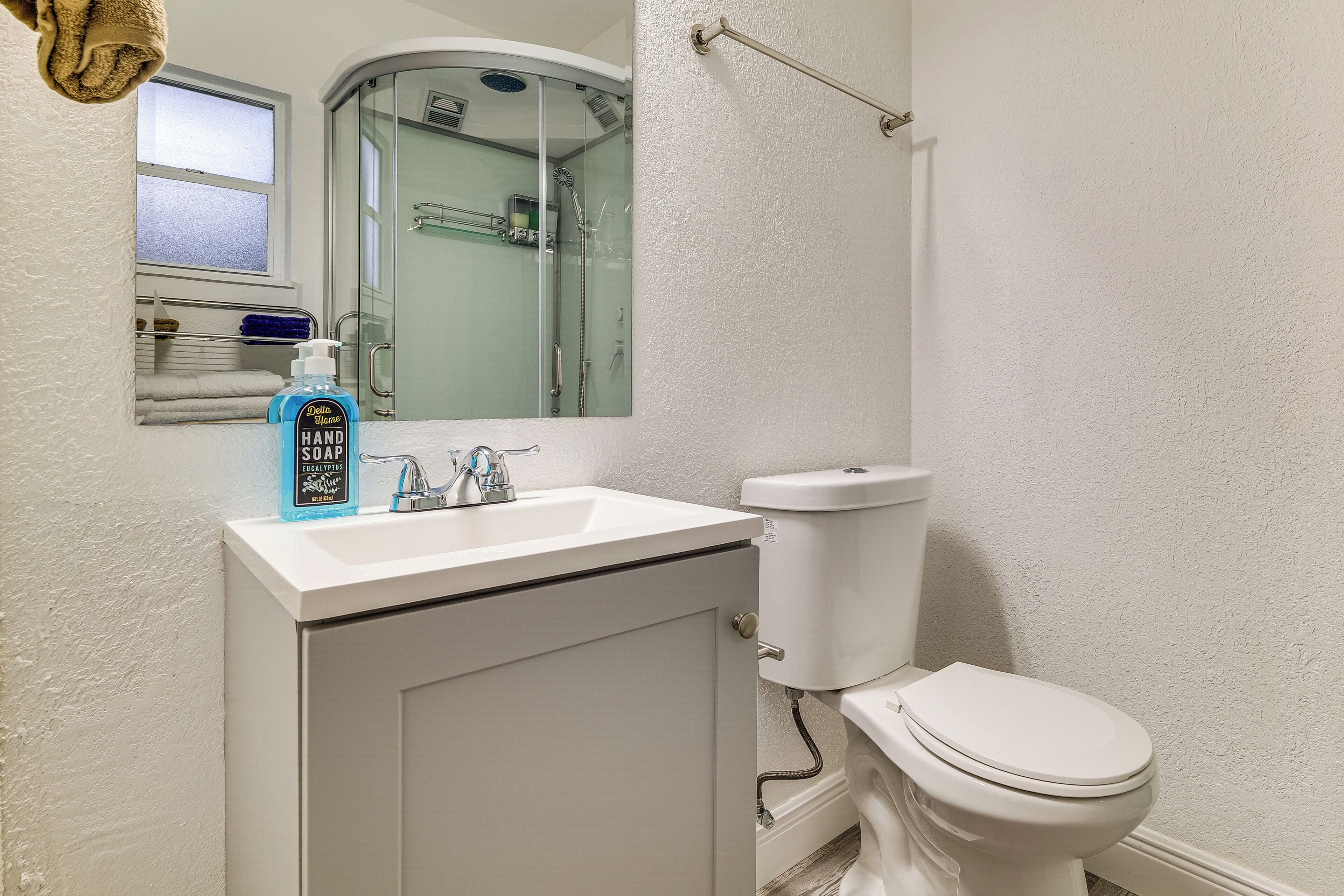 A bathroom with a white sink, a toilet, a glass shower enclosure, and a towel rack.