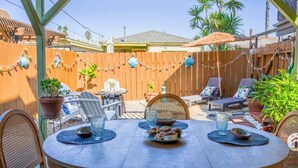 Eine Terrasse im Freien mit einem runden Tisch, Stühlen und einem Grill.