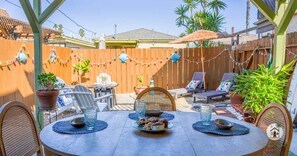 An outdoor patio with a round table, chairs, and a barbecue grill.
