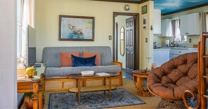 A living room with a sofa, a round coffee table, a chair, and a kitchen in the background.