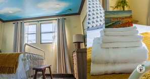 A hotel room with a bed, a window with curtains, a radiator, a lamp, and a sign with 'San Diego' on it.