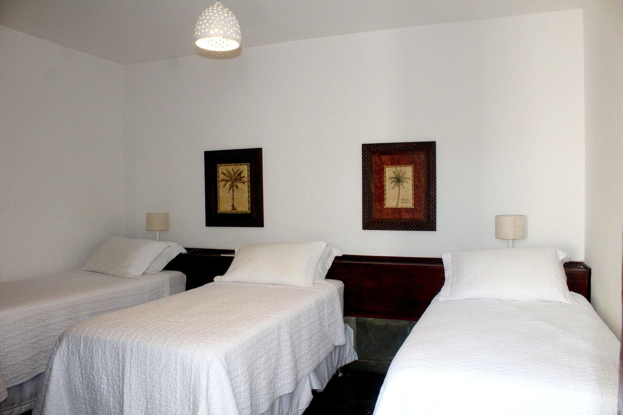 Una habitación de hotel con dos camas individuales, un ventanal grande y dos cuadros en la pared.