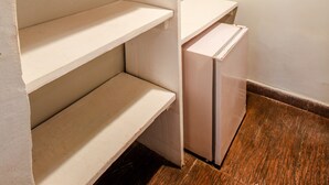 A walk-in closet with open shelves, a hanging rack, and a small table. - Rede Andrade Galeão (Porto Seguro)