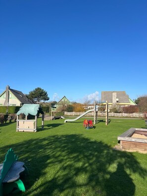 Ein Spielplatz mit Rutsche, Klettergerüsten und einem kleinen Spielhäuschen.