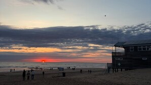 Une plage avec une tour de surveillance et un coucher de soleil en arrière-plan.