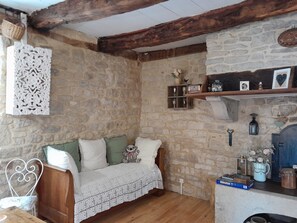 A cozy room with a stone wall, a wooden bench, a white crocheted bench, and a shelf with decorative items. - Holiday Home 'La Petite Authentique' with Private Terrace (Gaillac-d'Aveyron)