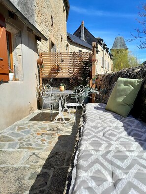 Un edificio de piedra con una cama, una mesa y sillas en un patio.