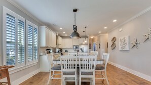 A spacious kitchen with white cabinets, a central island, and a dining area with white chairs.