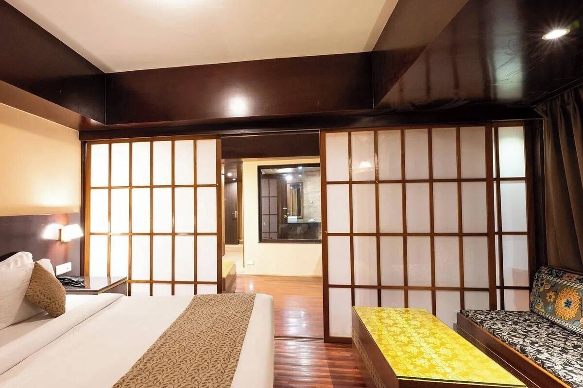 Een hotelkamer met een bed, nachtkastje, een bank en een schuifdeur van shoji-scherm.