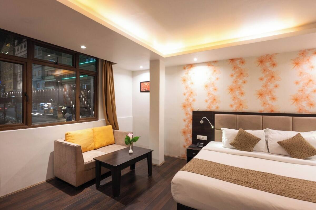 Een hotelkamer met een bed, een slaapbank, een klein tafeltje en een nachtkastje.
