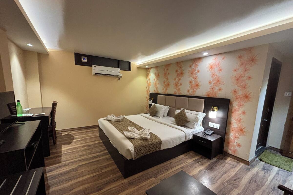 Een hotelkamer met een bed, nachtkastje, bureau, stoel en een airco.