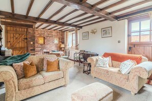 A cozy living room with two patterned sofas, a coffee table, and a brick fireplace.