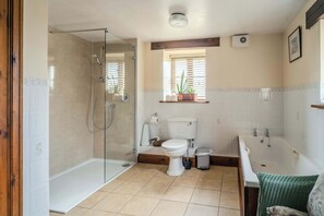 A bathroom with a glass-enclosed shower, a toilet, a bathtub, and a window with blinds.