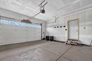 A garage with a white garage door, a door with a golden frame, and a concrete floor.