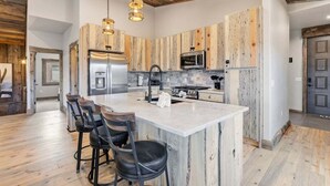 Een moderne keuken met een groot eiland, barstoelen en houten kasten.