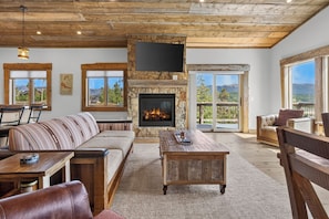 A spacious living room with a fireplace, large windows, and a view of the outdoors.