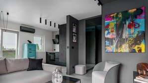 A modern living room with a sofa, a glass coffee table, and a unique curved chair. - AS HOME Niegaleria (Wrocław)